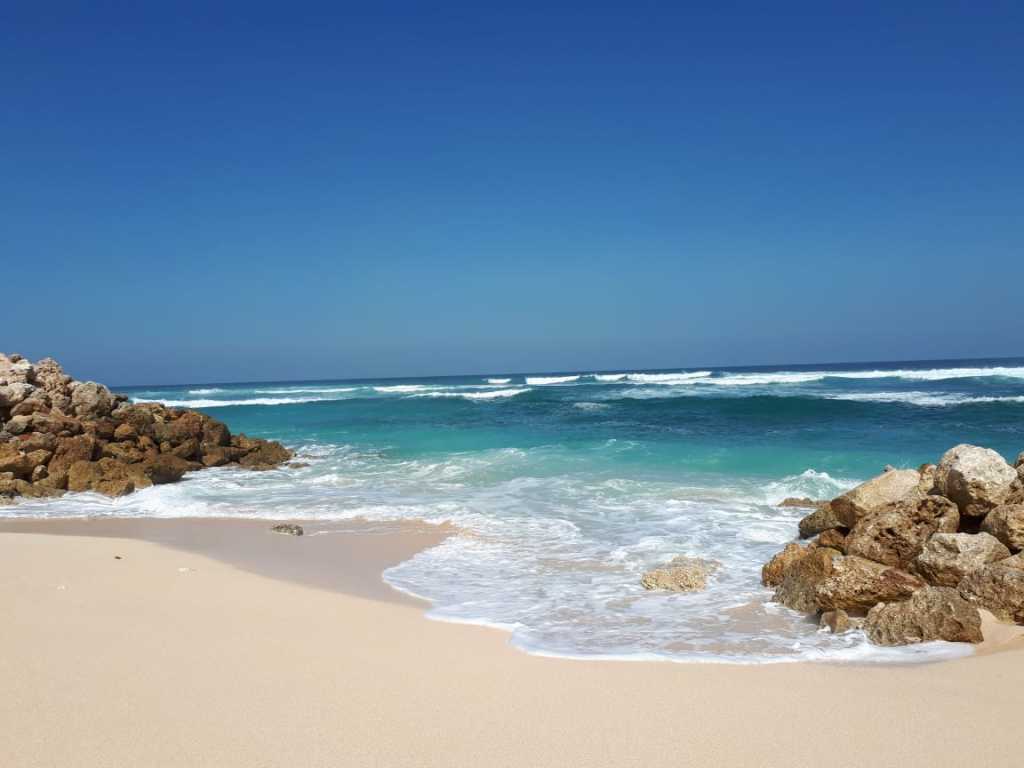 Pemandangan pasir putih dan ombak biru pantai melasti